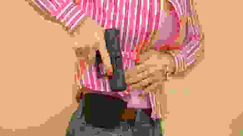 Women drawing a pistol from a waist holster.